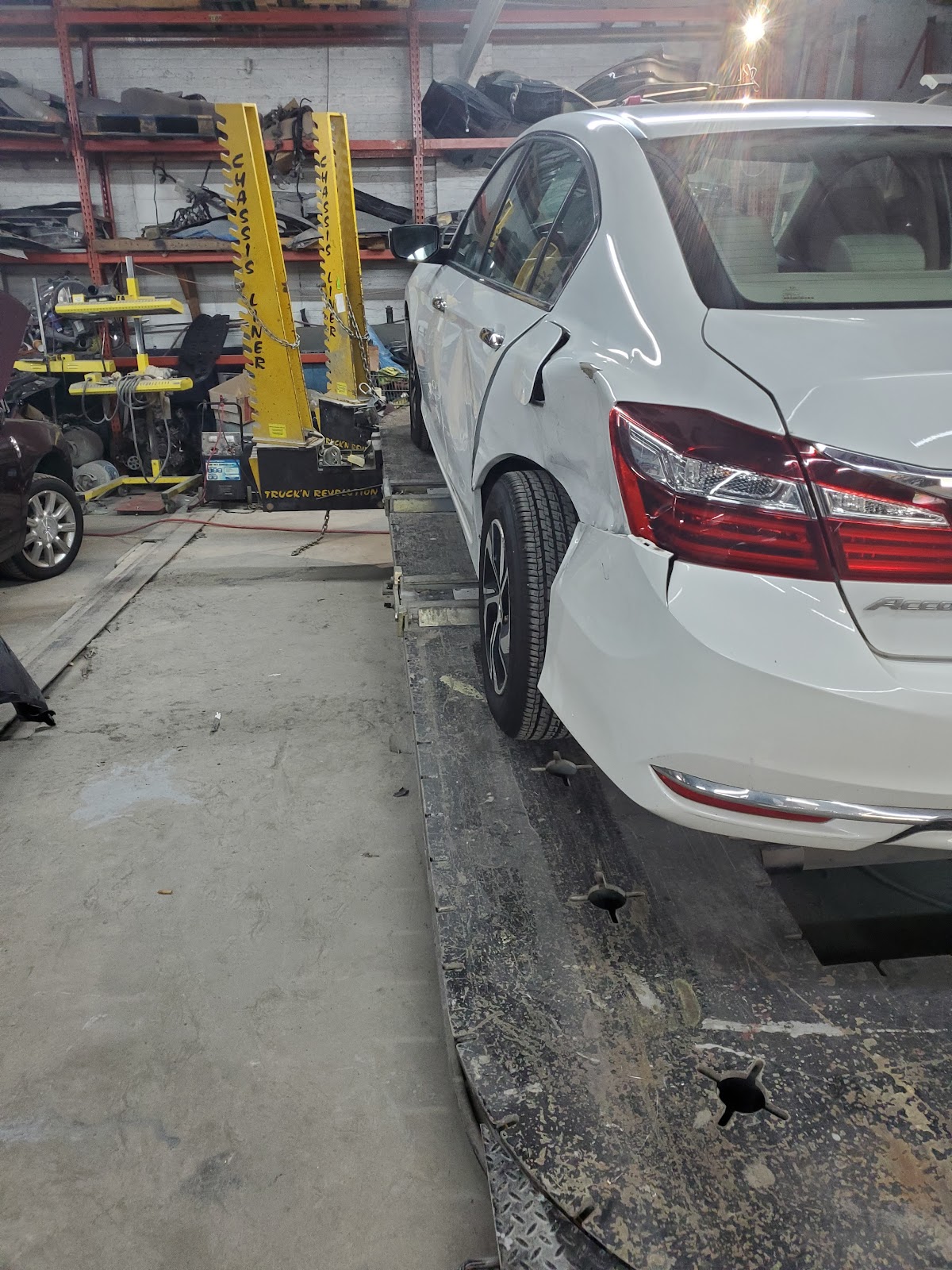 White Honda Accord with rear quarter-panel damage on the frame rack