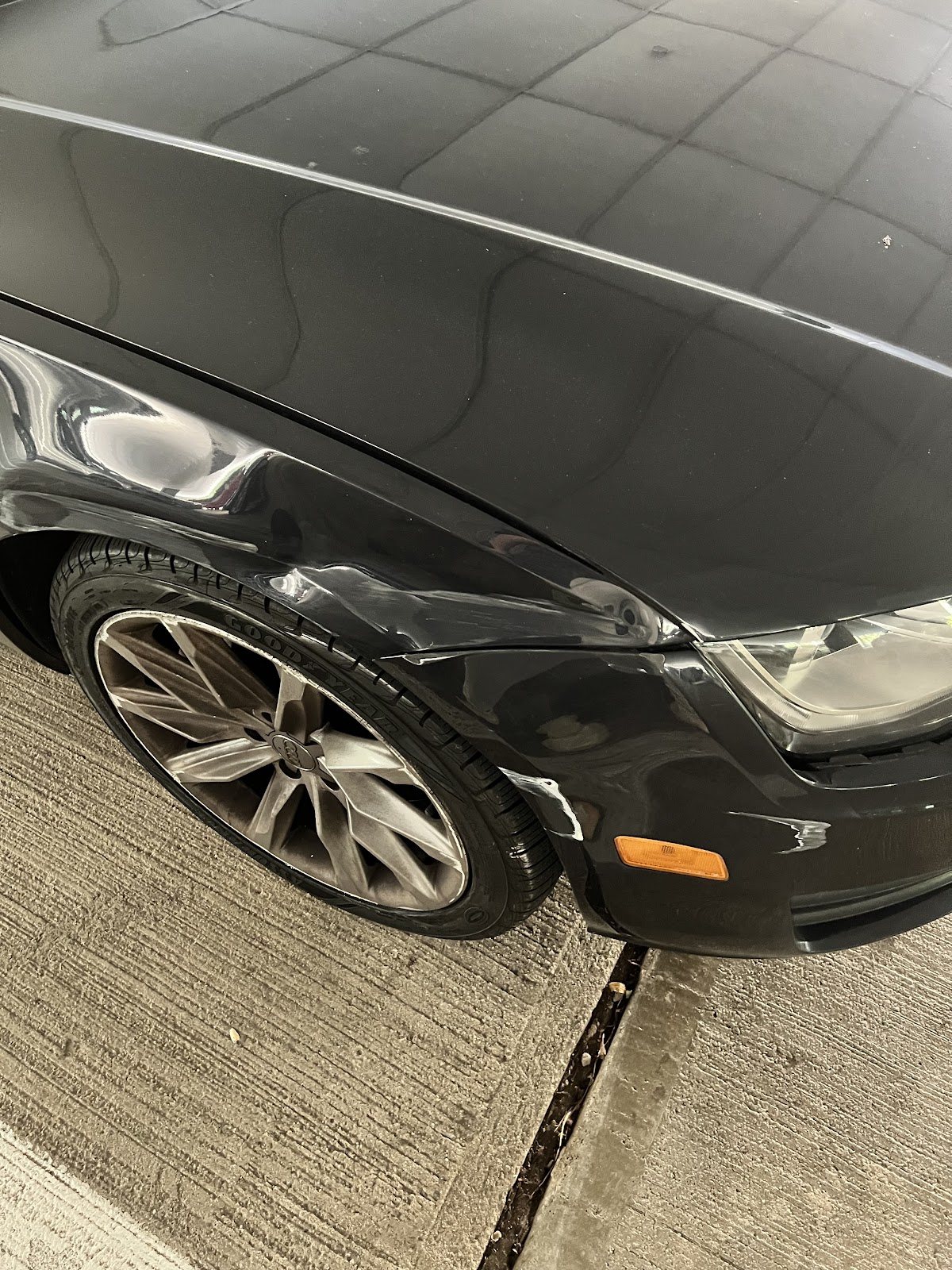 Black Audi with a dented front fender, before repair
